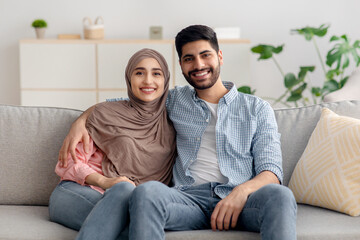 Happy Muslim Family Couple Sitting Together And Embracing At Home