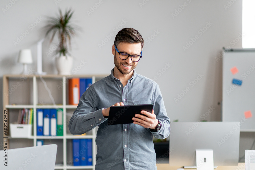 Aufkleber portrait of cheerful mature businessman using computer tablet in office, looking at screen and smili