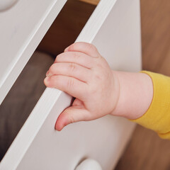 Danger for the baby to pinch the hand of the cabinet door or chest of drawers. Protect children from home furniture, kids safety