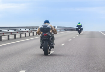 Motorcyclists on bikes ride on a country road.