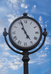 Street clock on the background of a cloudy sky