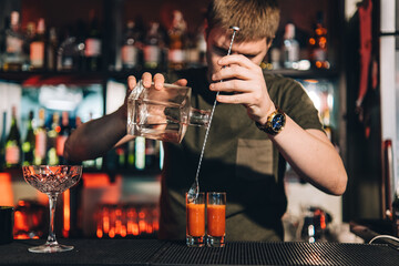 Vintage portrait of bartender creating cocktails at bar. Close up of alcoholic beverage preparation