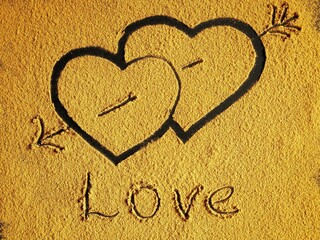 Hearts with an arrow on a yellow sand background with inscription Love. Valentine's day concept.