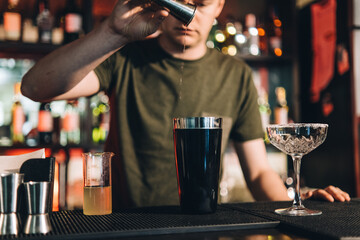 Vintage portrait of bartender creating cocktails at bar. Close up of alcoholic beverage preparation