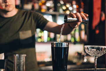Vintage portrait of bartender creating cocktails at bar. Close up of alcoholic beverage preparation