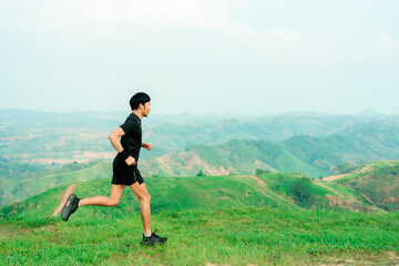 Obraz premium Portrait of an Asian male trail runner running. On the high mountains there are beautiful views. It's a trail running practice. on a bright day Behind is a beautiful mountain view.