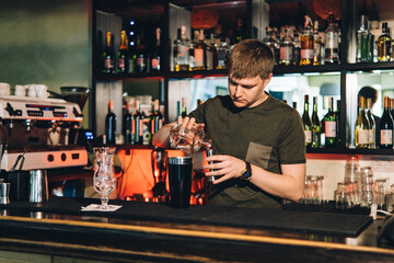 Vintage portrait of bartender creating cocktails at bar. Close up of alcoholic beverage preparation