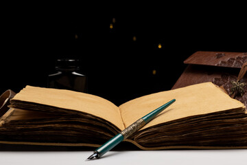 journal of ancient papyrus leaves with quill and embossed cover with ink bottle and black background