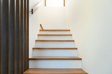 staircase wooden with wooden handrails on white wall in modern home. Interior structure design concept. Empty pathway of stairway