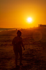 Fototapeta na wymiar Long shot of a woman walking at sunset on the beach