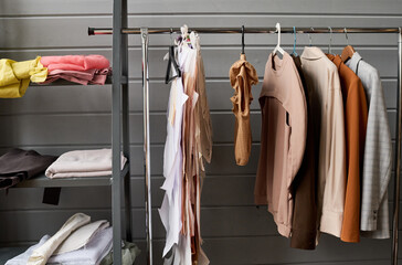 Part of long rack with variety of casual clothes of different colors hanging in modern boutique or workshop of tailor or fashion designer