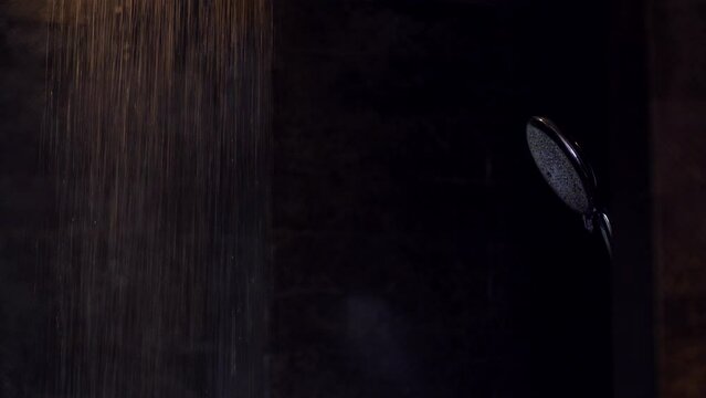 Water flowing from rain shower in batroom with dark black interior background