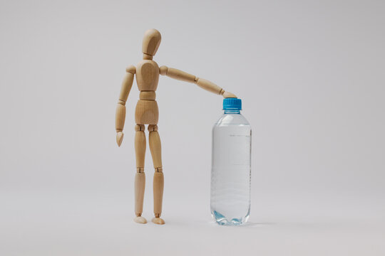 a wooden mannequin stands near a bottle of water on a white background