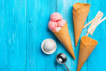 Berry and cream ice cream, waffle cups and a spoon on a blue background. Top view, copy space.