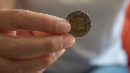 Fototapeta na wymiar Mano que muestra moneda de 2 pesos mexicanos