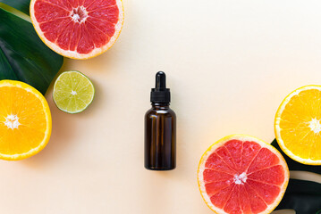 Vitamin C serum in an amber bottle with a pipette on a background of orange citrus fruits with...