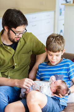 Proud dad introducing newborn baby to young uncle - family interactions