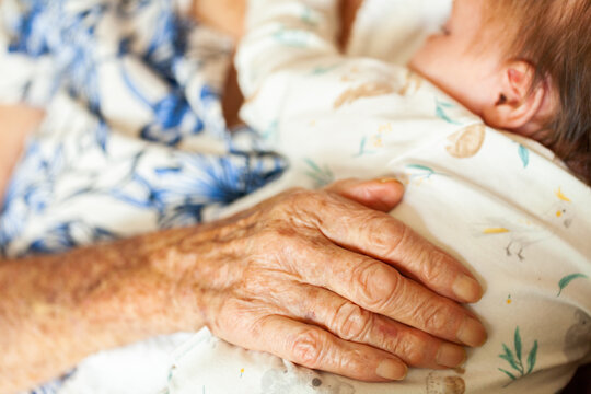 Great grandmothers hand on sleeping newborn baby