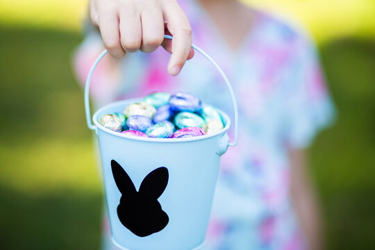 Little girl holding a bucket of foil wrapped Easter eggs