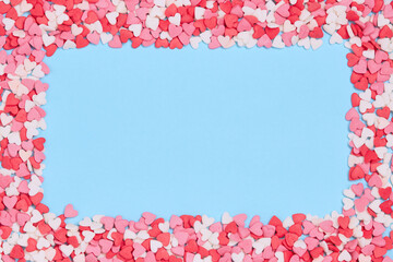 Candies hearts of pastel colors on blue paper. Flat lay. Background of brightly colored candy hearts for Valentine's Day. Valentine day greeting card or banner.