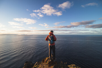 Passionate backpacker at 24 years old stands on the edge of a cliff in a place called Cristo Rei, Camara de Lomos, Madeira, belonging to Portugal. Sunrise on the Atlantic coast