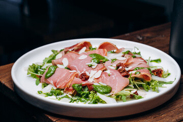 salad with prosciutto and avocado with avocado sauce on a white plate