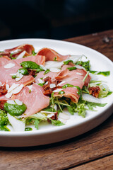 salad with prosciutto and avocado with avocado sauce on a white plate