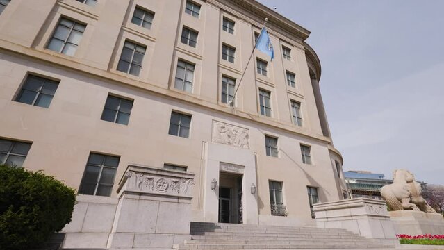 The FTC headquarters building in the Federal Triangle area of downtown Washington, D.C. seen from the Constitution Avenue NW entrance on an early spring day.Static, low-angle wide shot with no people.