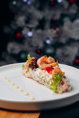 Olivier salad in a white plate in a festive atmosphere. A traditional Russian dish for Christmas and New Year