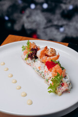 Olivier salad in a white plate in a festive atmosphere. A traditional Russian dish for Christmas and New Year