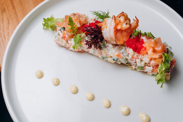 Olivier salad in a white plate in a festive atmosphere. A traditional Russian dish for Christmas and New Year