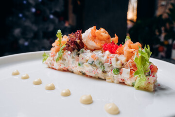 Olivier salad in a white plate in a festive atmosphere. A traditional Russian dish for Christmas and New Year