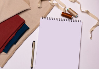 Notepad mockup with colorful fabric and sewing threads on white background