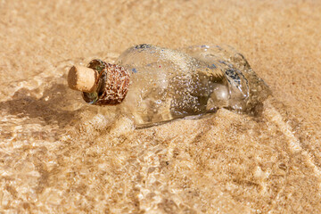 Flasche mit Korken im Wasser an einem Strand der Küste.