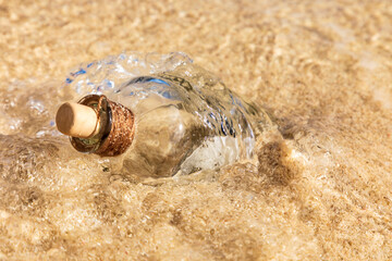 Alte leere Flasche, umspült vom Wasser am Ozean.