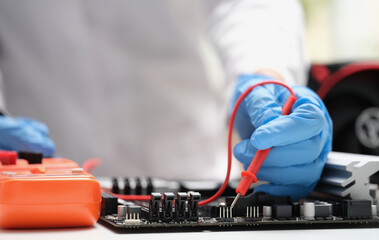 Technician measuring voltage of in computer mainboard using electronic digital multimeter