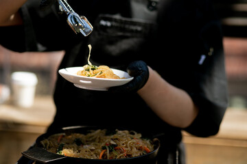 Cropped image of chef serving glass noodles at a catered event