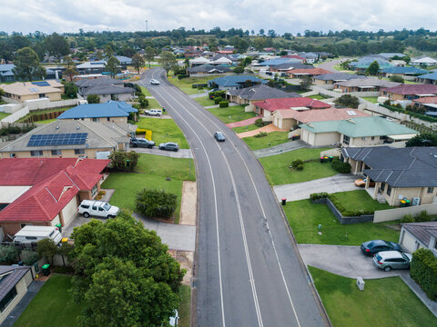 Car driving down street in residential area with houses and cars parked in driveways