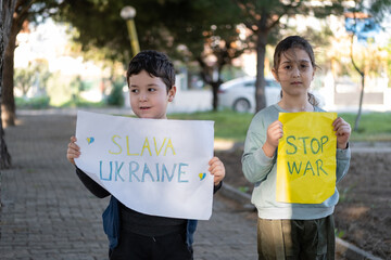 Children holding posters that say stop the war and slava Ukraine means to glory to Ukraine.