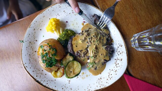 Hand cutting meat at lunch time top view of delicious gourmet food on plate