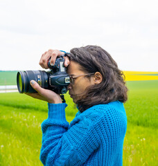 photographe en shooting sur fond de champs de colza et de blé vert