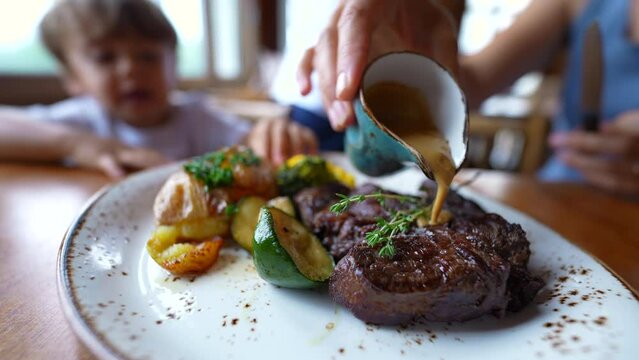 Food on plate person pouring sauce into red meat at restaurant
