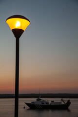 Long shot of a street light and a fish boat in a sunset beach