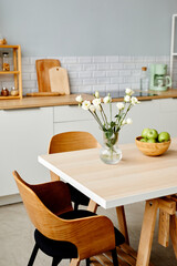 Vertical background image of fresh white flowers on dinner table in white kitchen interior decorated for Spring