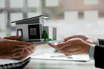 Real estate agents are carrying a housing model of the project to be forwarded to customers as home delivery. Real estate trading ideas and bank loans for buying and selling houses and land.