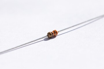 A close up portrait of a 330 ohm resistor with a 5% tolerance. The electric component is isolated on a white background and is ready to be used in an electronic circuit or soldered on a PCB.