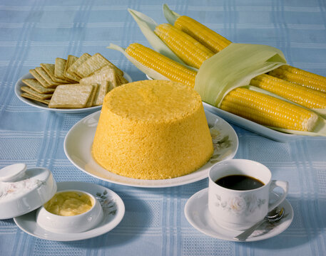 Corn couscous at the table with a cup of coffee and boiled corn cobs. Typical food from the northeast region of Brazil.