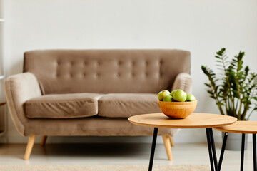 Background image of green apples bowl on wooden table in minimal living room interior with cozy couch, copy space