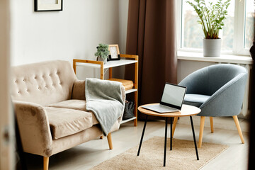 Background image of open laptop with blank white screen on coffee table in cozy minimalistic interior, copy space