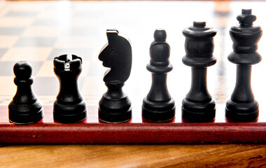 Chess game, board and wooden black pieces.